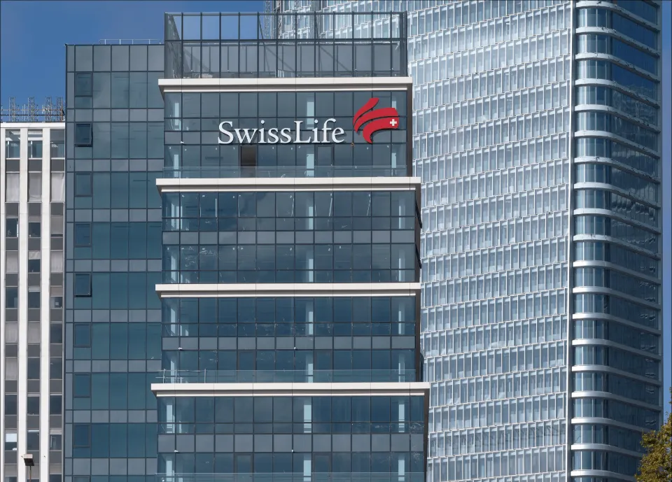 Façade d'un immeuble moderne avec le logo de Swiss Life et son emblème rouge sur fond bleu.