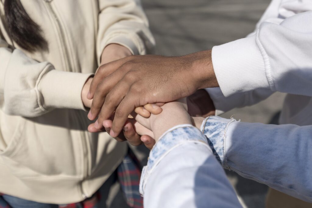 Plusieurs mains de personnes différentes empilées les unes sur les autres, symbolisant l'unité et le soutien.